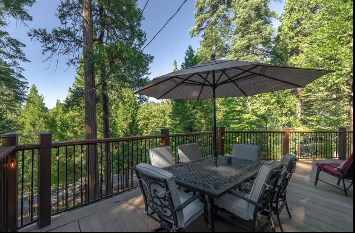 Outdoor dining table beneath an umbrella on the forest deck